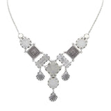 The Firefly Ocean Elaborate Soft Necklace features an ornate pendant with geometric and filigree designs, plus three shell-shaped charms—handmade in Guatemala.