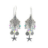 The Playa Starfish Fringe Soft Earrings by Firefly feature intricate silver dangles with colored beads, shell-shaped charms, and starfish pendants. Handmade in Guatemala, these hypo-allergenic earrings blend unique style and artisan craftsmanship.