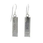 A pair of Beach Glass Rectangle Soft Earrings by Firefly, featuring silver rectangles handmade in Guatemala, each engraved with “dream” or “hope,” hanging from simple hooks against a white background.