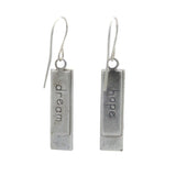 A pair of Beach Glass Rectangle Soft Earrings by Firefly, featuring silver rectangles handmade in Guatemala, each engraved with “dream” or “hope,” hanging from simple hooks against a white background.