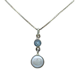 The Freshwater Pearl Round Blue Topaz Necklace by Mediterranean Artists Co. features a small round blue topaz above a larger white freshwater pearl, both set in 925 sterling silver.