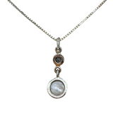 The Freshwater Pearl Round Blue Topaz Necklace by Mediterranean Artists Co. Sterling Silver features a thin 925 silver chain with double pendants: a small round freshwater pearl and a larger marbled blue topaz stone.