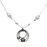The Sterling Silver Circles Freshwater Pearl Station Chai Necklace by Mediterranean Artists Co. Sterling Silver features a circular pendant with three interlocking rings, two small spheres, and a chain accented by irregular white freshwater pearls.