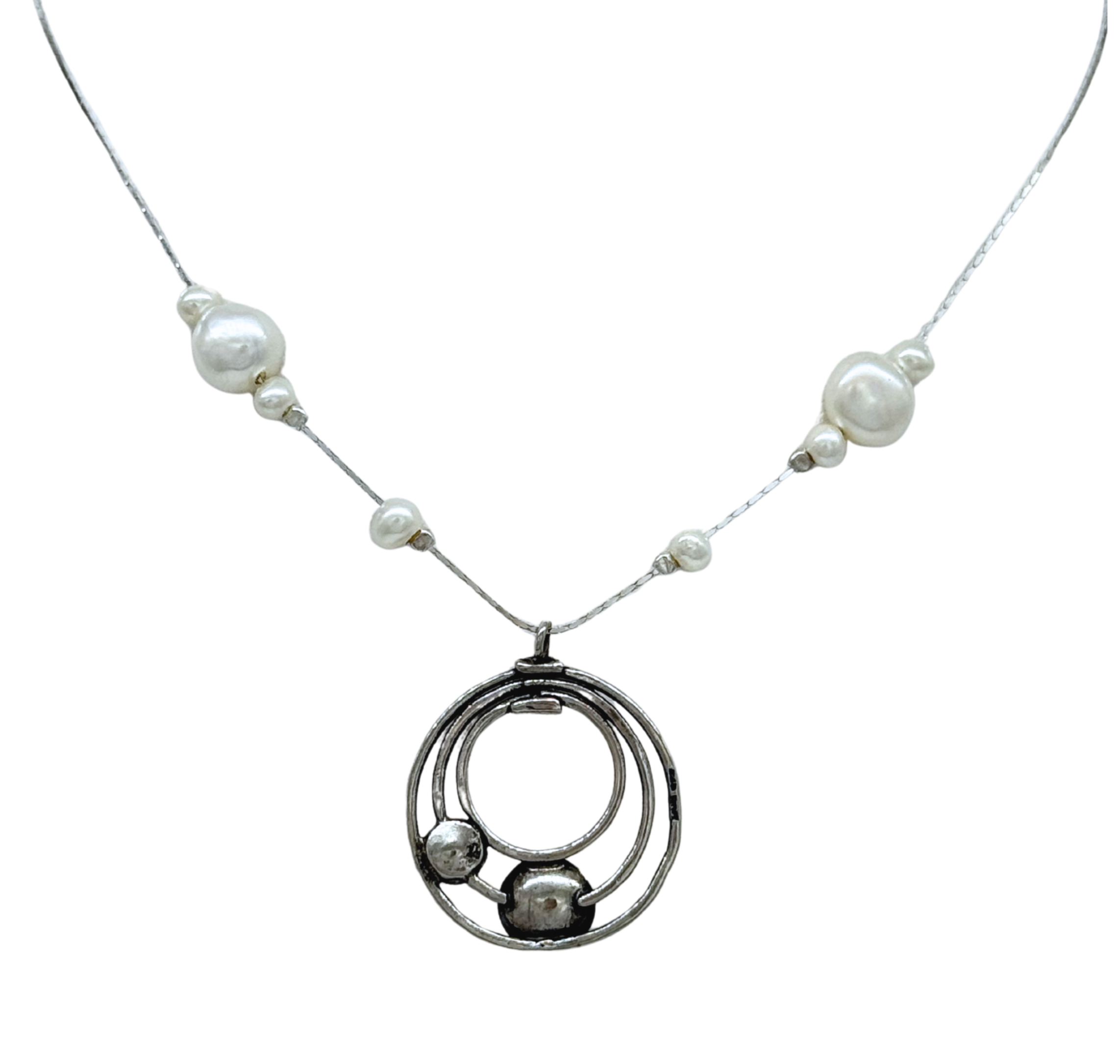 The Sterling Silver Circles Freshwater Pearl Station Chai Necklace by Mediterranean Artists Co. Sterling Silver features a circular pendant with three interlocking rings, two small spheres, and a chain accented by irregular white freshwater pearls.
