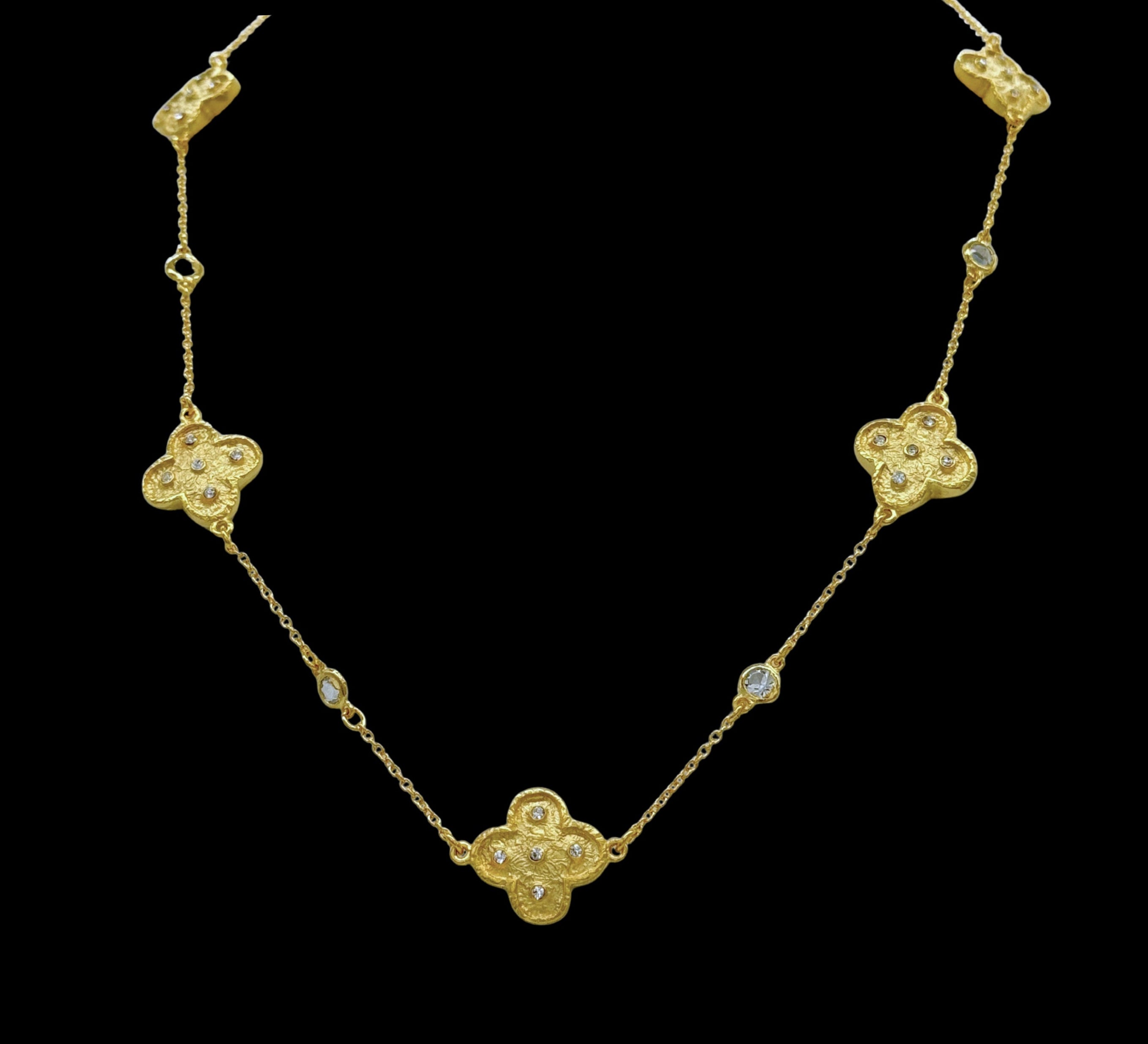 The Be-Je Designs Gold Clovers & CZ Insets Necklace features three clover-shaped pendants with cubic zirconia on a delicate, adjustable 14kt gold chain, adding elegance to any look.
