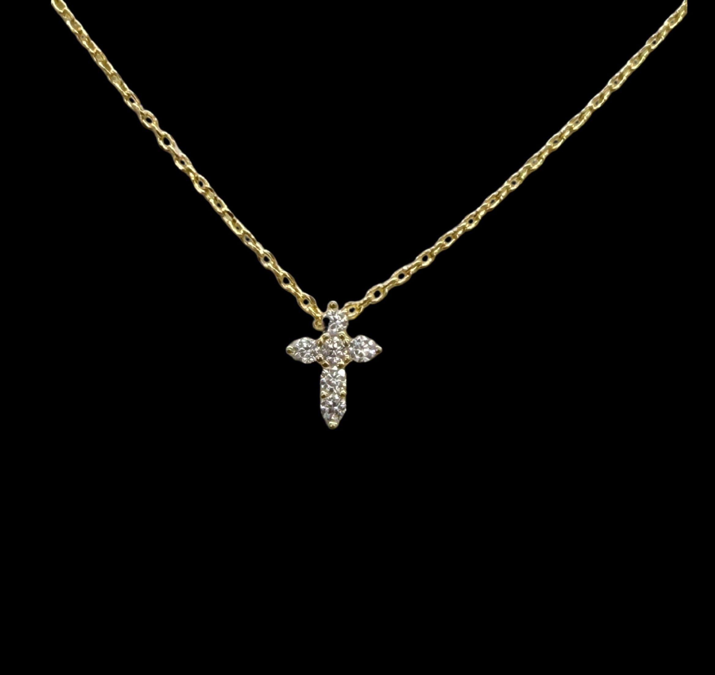 The Be-Je Designs Small Gold Pave CZ Cross Necklace features a 14kt gold adjustable chain and a shimmering cubic zirconia cross pendant, elegantly set against a solid black background.