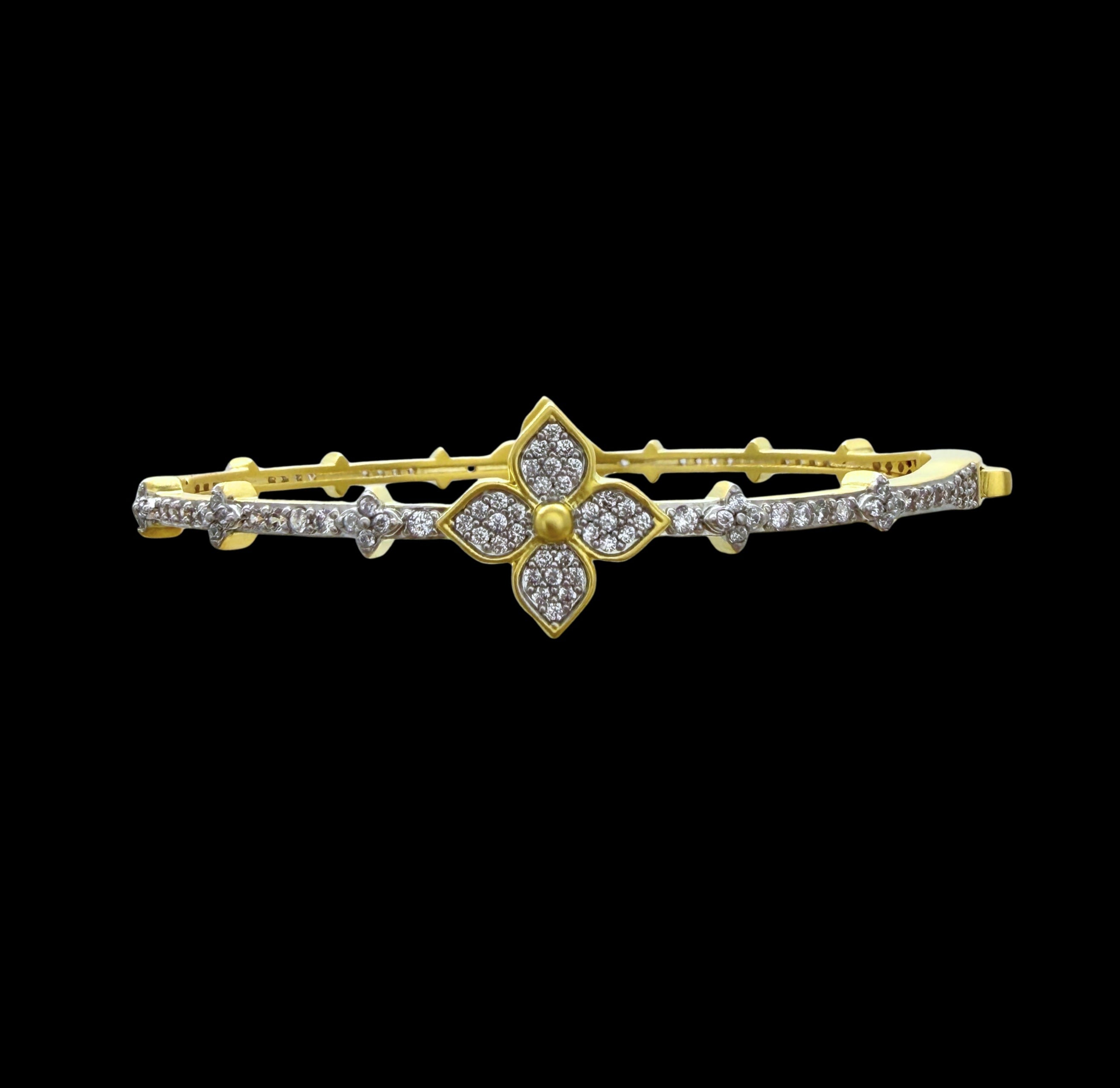 Be-Je Designs' Gold Pave Clover CZS Bracelet features a central clover design encrusted with sparkling stones and additional accents along the band—a chic, everyday accessory that stands out against a black background.