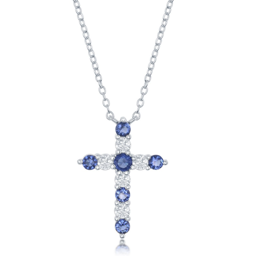 The Classic of New York Sterling Silver Birthstone Cross (September) Necklace showcases a cross pendant with alternating blue sapphires and clear stones in a symmetrical design, elegantly hanging from a fine chain.
