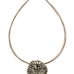 The Origin Textured Round Organic Pendant Gold/Blue Necklace is a gold-tone wire choker featuring an organic, textured round pendant with dark blue accents and a magnetic closure.