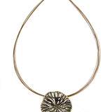 The Origin Textured Round Organic Pendant Gold/Blue Necklace is a gold-tone wire choker featuring an organic, textured round pendant with dark blue accents and a magnetic closure.