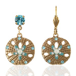 Anne Koplik Designs, Inc. ER: Gold Tone Sand Dollar Dangle earrings feature intricate cutouts, round turquoise gemstones, pearl accents, and blue and white details for a stylish look.