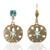 Anne Koplik Designs, Inc. ER: Gold Tone Sand Dollar Dangle earrings feature intricate cutouts, round turquoise gemstones, pearl accents, and blue and white details for a stylish look.