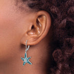 Close-up of a persons ear with curly hair wearing Presco/Quality Gold’s Crystal Blue Starfish Earrings, crafted in sterling silver and accented with blue and clear Swarovski crystals.