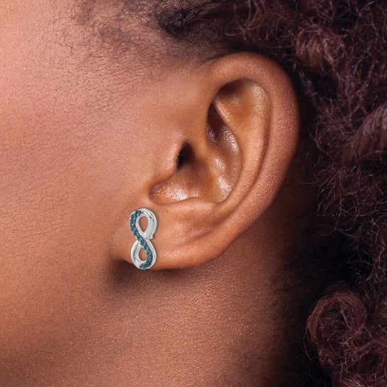 A close-up shows a person with curly brown hair wearing Presco/Quality Golds Crystal Eternity Post Earrings—sterling silver earrings in an infinity shape with small blue gems along the edge.