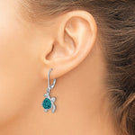 A close-up of a woman’s ear showcases Presco/Quality Gold’s Crystal Teal Turtle Dangle Earrings, with a green and silver shell design. Her pulled-back hair reveals the unique sterling silver accessory.
