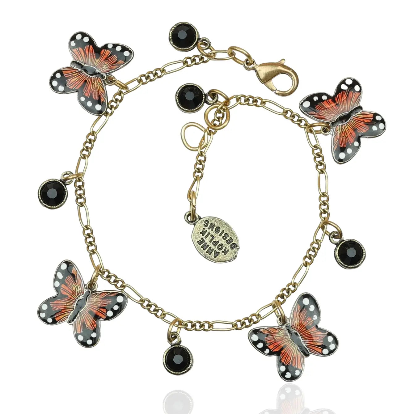 The Orange Monarch Butterflies w/4 Drops Bracelet by Anne Koplik Designs, Inc. features five hand-enameled orange and black butterfly charms, four black gemstone drops, and an oval tag engraved with "shine bright.
