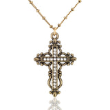 The Anne Koplik Designs Brass Filigree Crystal Cross Necklace features an ornate, vintage-style crystal-lined cross pendant, displayed on a reflective white background.