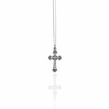 The Mini Crystal Cross Necklace by Anne Koplik Designs, Inc. features a silver chain with an ornate crystal cross pendant, shown against a white background. This religious jewelry piece has intricate details and a reflective accent below the cross.