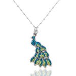 The Whimsy Stone & Enamel Male Peacock Necklace by Anne Koplik Designs features a peacock pendant adorned with blue and green gemstones, hand-enameled details, and hangs from a delicate beaded chain.