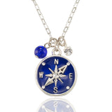 The Anne Koplik Designs, Inc. NK: Blue Enamel & Stone Compass Jumble is a silver necklace featuring a blue enamel compass pendant marked N, S, E, W, with a blue bead and clear gemstone charm on a delicate chain.