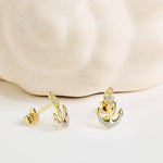 Shanore's Gold Vermeil & White Sapphire Anchor Post Earrings, displayed on light beige marble, feature sparkling white sapphires—a stunning nautical jewelry piece.