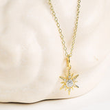 Shanore’s Gold Vermeil & White Sapphire Sun Mini Necklace is shown with its sun-shaped pendant against a cream, textured backdrop.