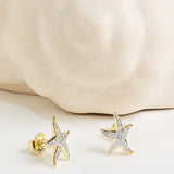 The Shanore Gold Vermeil & White Sapphire Starfish Post Earrings are displayed in front of a white marble textured sculpture.