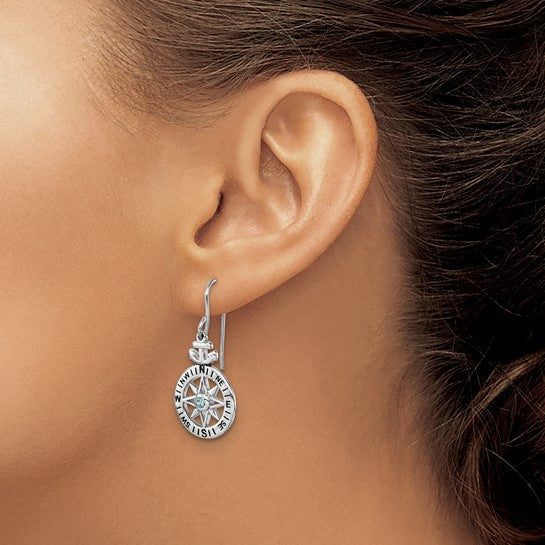 A close-up of a woman’s ear with her hair pulled back, showcasing Presco/Quality Gold Sterling Silver Compass/Anchor Crystal Earrings featuring engraved letters and an intricate design.