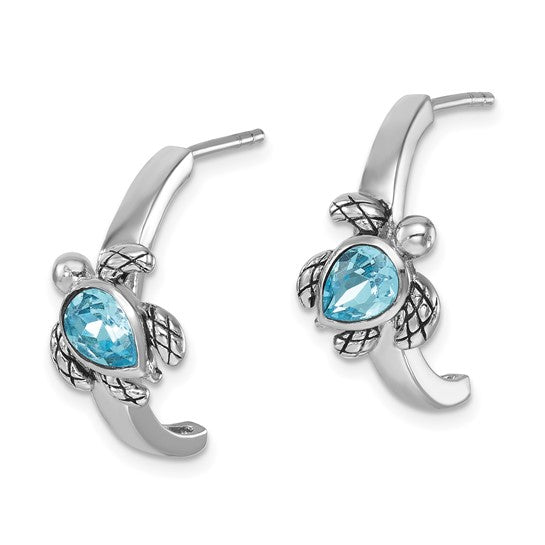 The Presco/Quality Gold Crystal Half-Hoop Post Turtle Earrings feature blue teardrop gemstones as shells, with curved sterling silver hoops and textured detailing on the turtles’ limbs and heads.