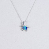 The Mosaico/.925 NK: Mosaic Mini Waving Turtle Aurora A pendant features a silver turtle with a blue and green gemstone shell, shown on a light gray background.