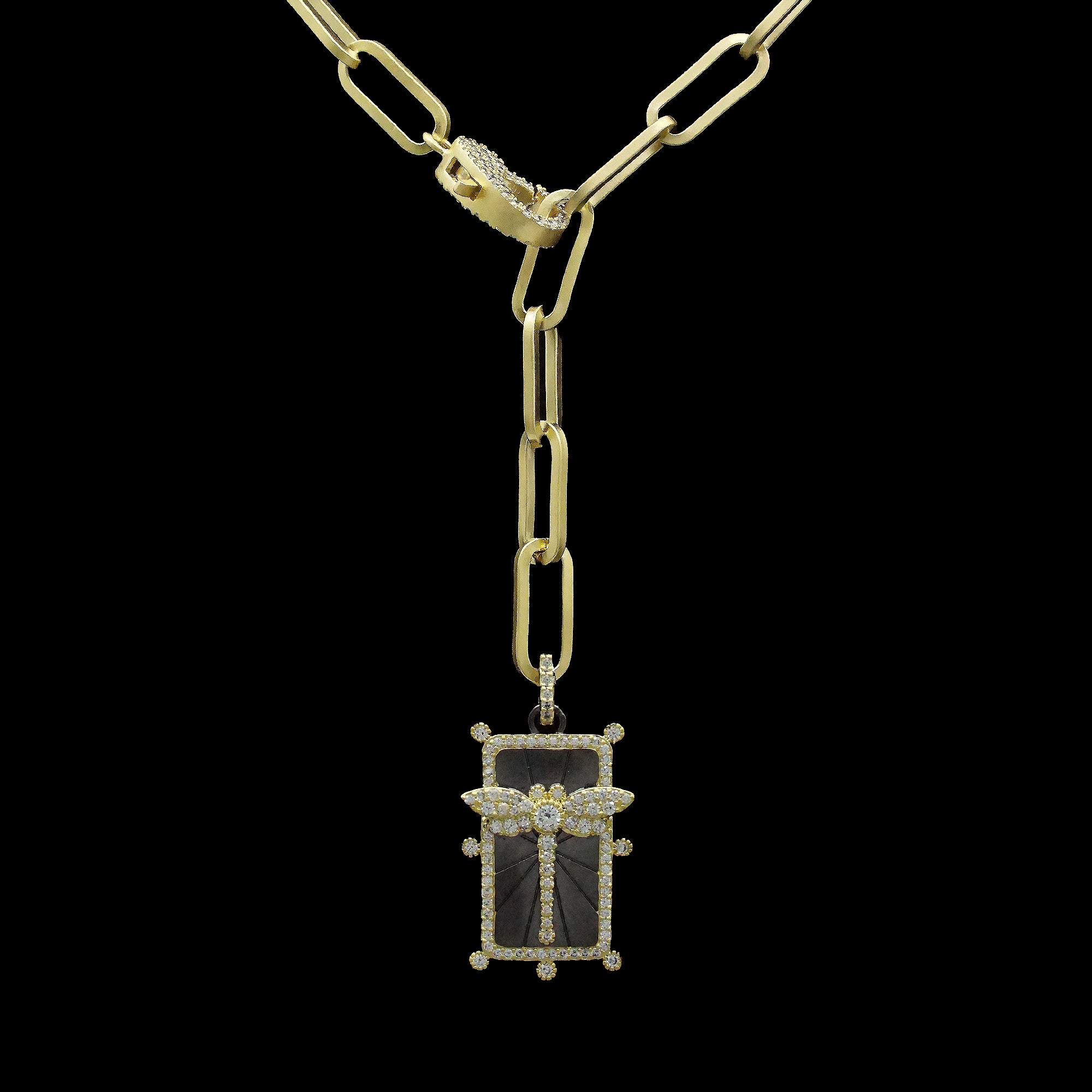 The Be-Je Designs Gold Paperclip Necklace features elongated links, a pave lobster claw, and a rectangular pendant with a stylized dragonfly design set against black cubic zirconia.