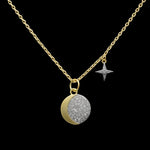 Be-Je Designs' Gold Pave Disc Crescent Moon & Small Starburst Charm Necklace features a 14kt gold, adjustable chain with moon and star charms—both accented with diamonds—displayed on a black background.