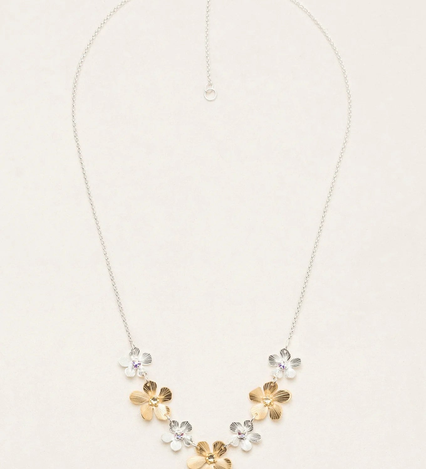 The Plumeria Classic Silver/Gold Necklace by Holly Yashi features a silver chain with five handcrafted floral pendants—three gold, two silver—in a V-shape and an adjustable clasp for the perfect fit.