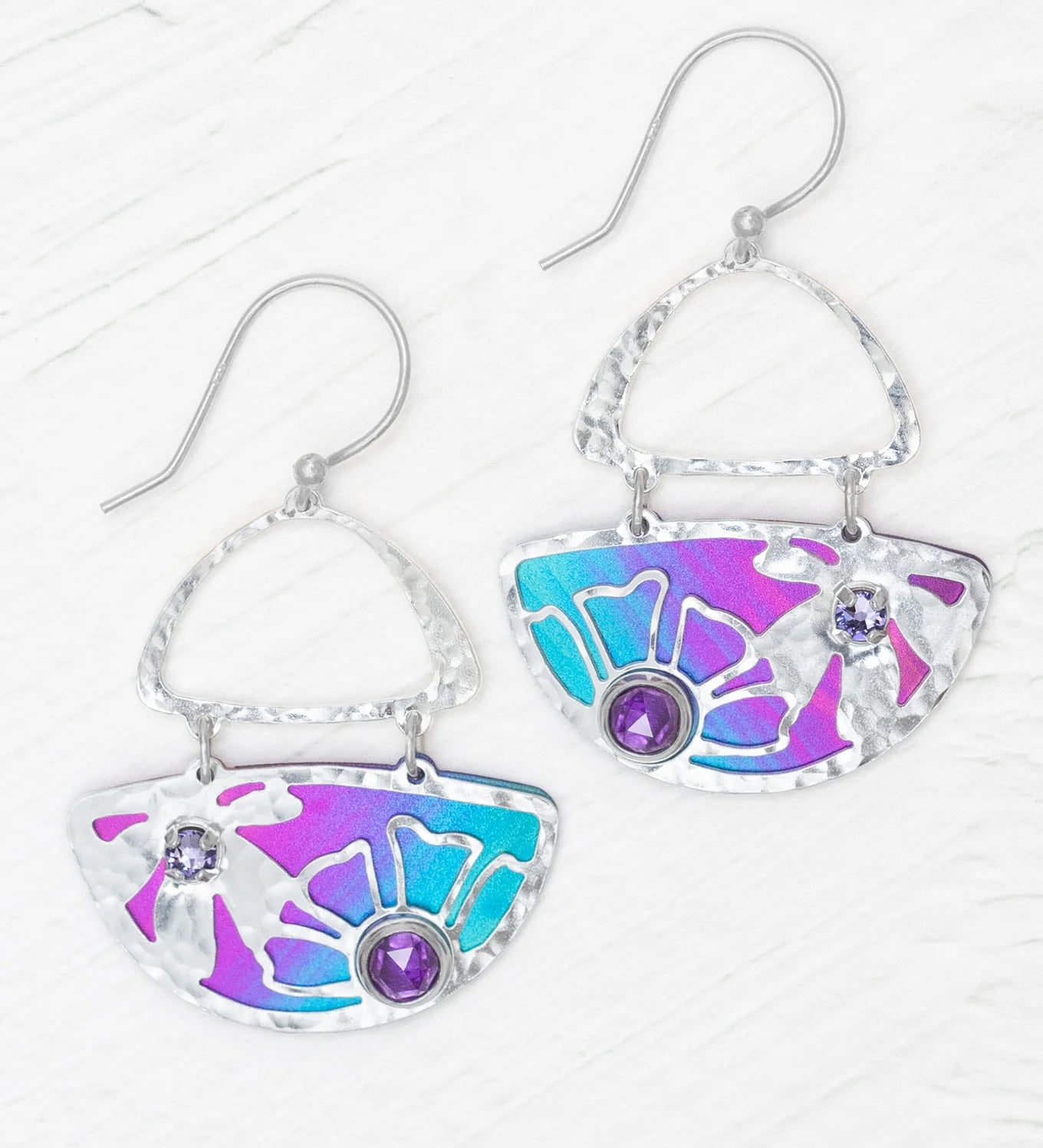 The Demi Calypso Earrings by Holly Yashi are hammered silver drop earrings with blue and purple enamel fan shapes, each adorned with two round purple gemstones and finished with sterling silver posts.