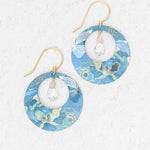 The Claire Sky Blue Earrings by Holly Yashi feature handcrafted round frames with blue, green, and gold floral patterns, gold hooks, and a clear faceted bead at the center—perfect for any occasion.