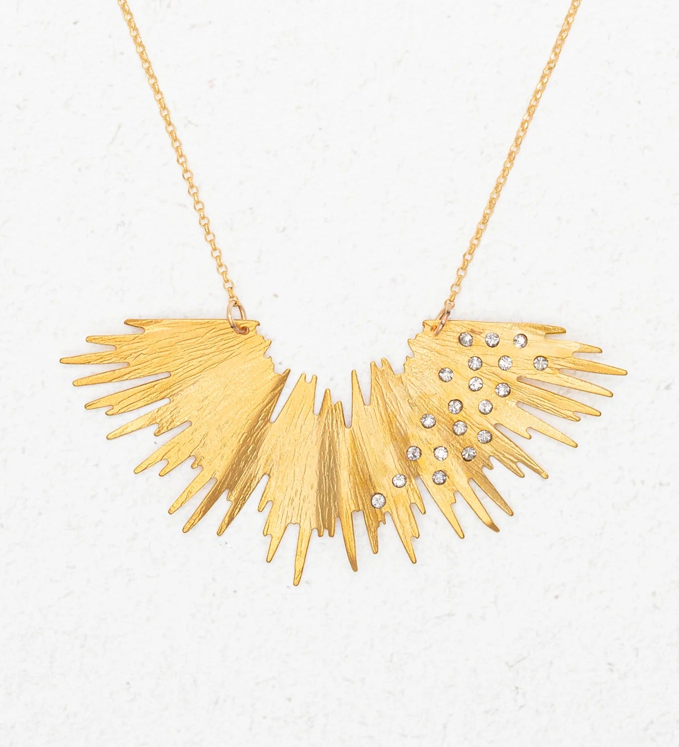 The Aster Necklace-Gold Necklace by Holly Yashi features a sunburst design with jagged rays and sparkling crystals, radiating golden brilliance against a plain white background.