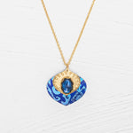 The Arabella Sapphire Blue Necklace by Holly Yashi features a vibrant glass stone set in textured gold with an adjustable pendant for the perfect fit.