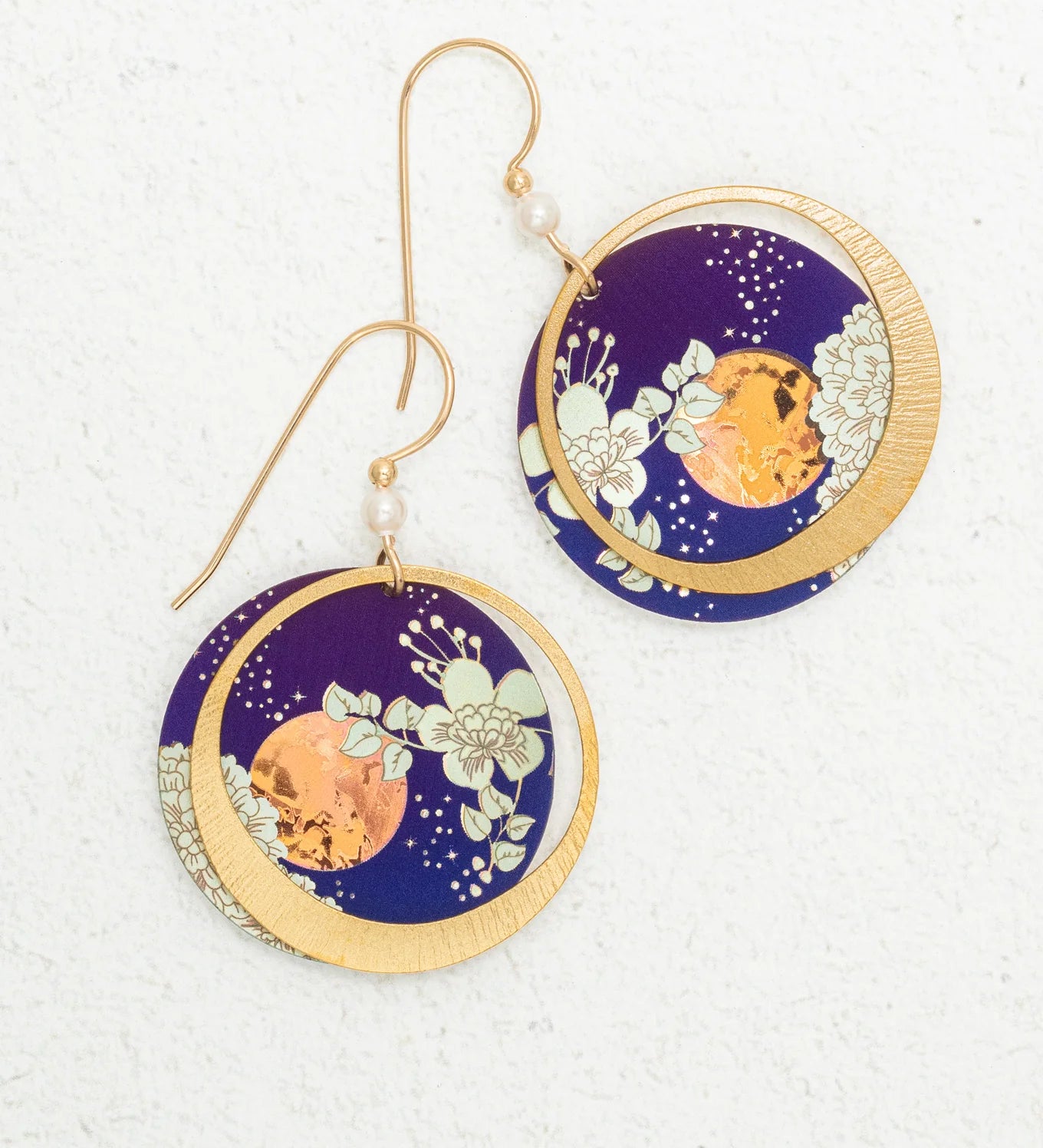 Luna Earrings/Blue Moon by Holly Yashi: Circular earrings with gold hooks, featuring a gold crescent moon over deep blue with white floral designs and an orange accent. Hypo-allergenic niobium—safe for sensitive ears.