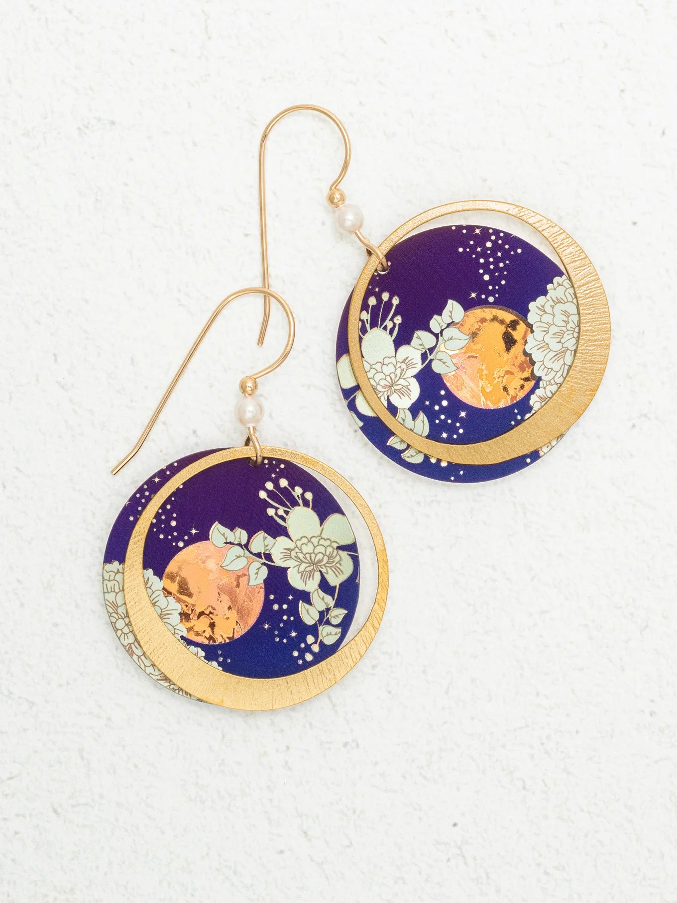 Luna Earrings/Blue Moon by Holly Yashi: Circular earrings with gold hooks, featuring a gold crescent moon over deep blue with white floral designs and an orange accent. Hypo-allergenic niobium—safe for sensitive ears.