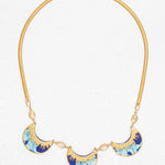 The Selena Necklace-Midnight Blue by Holly Yashi features three crescent blue, turquoise, and gold enamel pendants on a gold snake chain with oval crystal accents, shown on a white background.