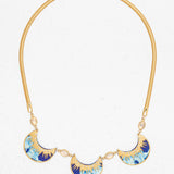 The Selena Necklace-Midnight Blue by Holly Yashi features three crescent blue, turquoise, and gold enamel pendants on a gold snake chain with oval crystal accents, shown on a white background.