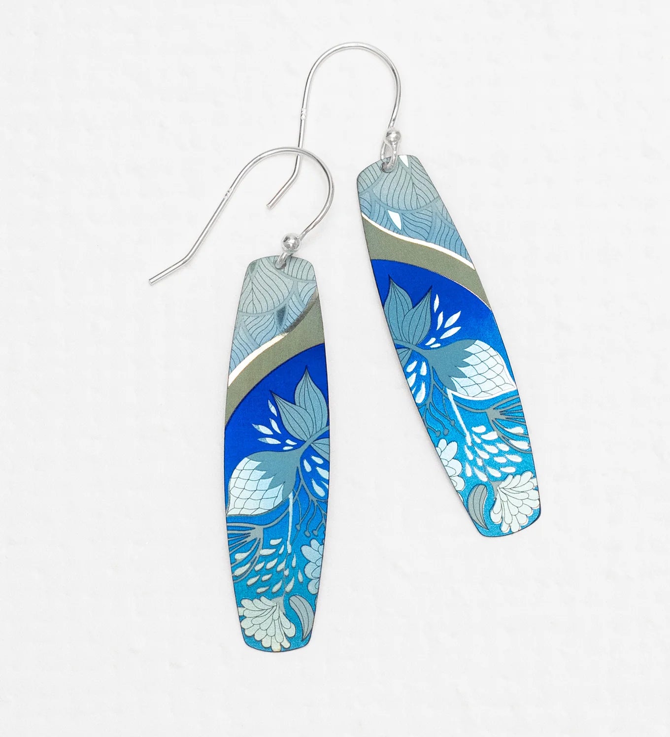 The Malia Kai Blue Earrings by Holly Yashi are long, rectangular handcrafted niobium earrings with silver hooks, featuring blue with white and light blue floral designs and a metallic accent. Hypoallergenic—ideal for sensitive ears.