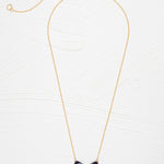 The Blooming Butterfly Blue Radiance Necklace by Holly Yashi features a gold adjustable chain and an iridescent niobium butterfly pendant with gold and turquoise accents, shown on a white textured background—a vibrant statement piece.