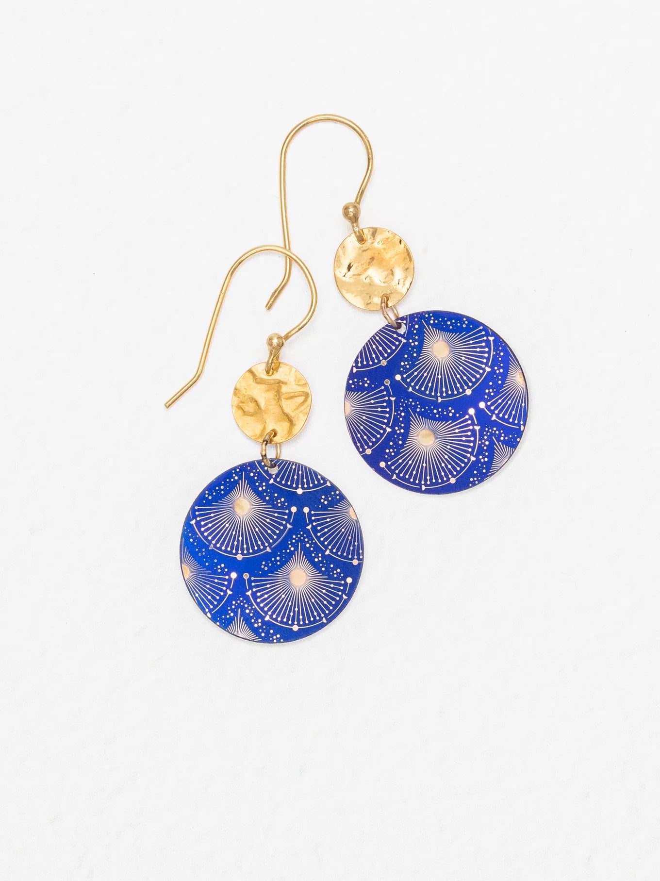 The Danica Earrings in Midnight Blue by Holly Yashi feature handcrafted dangle design with hammered gold circular tops and larger blue round pendants accented by a decorative white and gold fan pattern. Displayed on a white background, these Niobium earrings offer unique style.