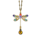 The Stone Dragonfly w/Drop Necklace by Anne Koplik Designs, Inc. features a gold dragonfly pendant with red, purple, green, and blue gemstones on antiqued brass and a round amber drop.