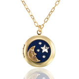 The Celestial Night Sky Moon and Stars Crystal Locket Necklace by Anne Koplik Designs, Inc. features a gold crescent moon, silver star, and crystals on a dark blue background, hanging from a delicate gold chain for timeless elegance.