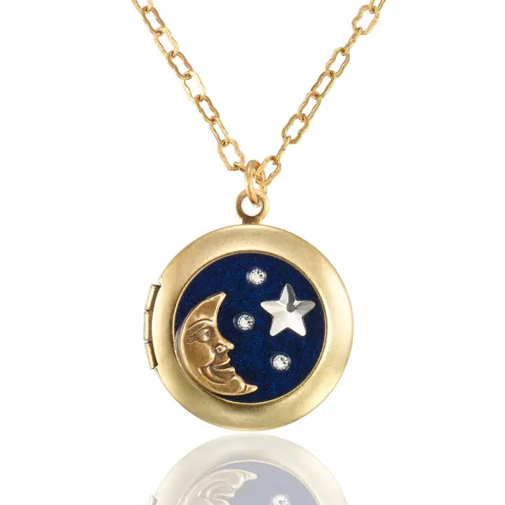 The Celestial Night Sky Moon and Stars Crystal Locket Necklace by Anne Koplik Designs, Inc. features a gold crescent moon, silver star, and crystals on a dark blue background, hanging from a delicate gold chain for timeless elegance.