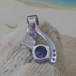 The Jewelry Network Caribbean Opal 3 Triangles/Round Amethyst Pendant rests on a textured white seashell, its modern design highlighted against a softly blurred background of sand with blue and beige accents.
