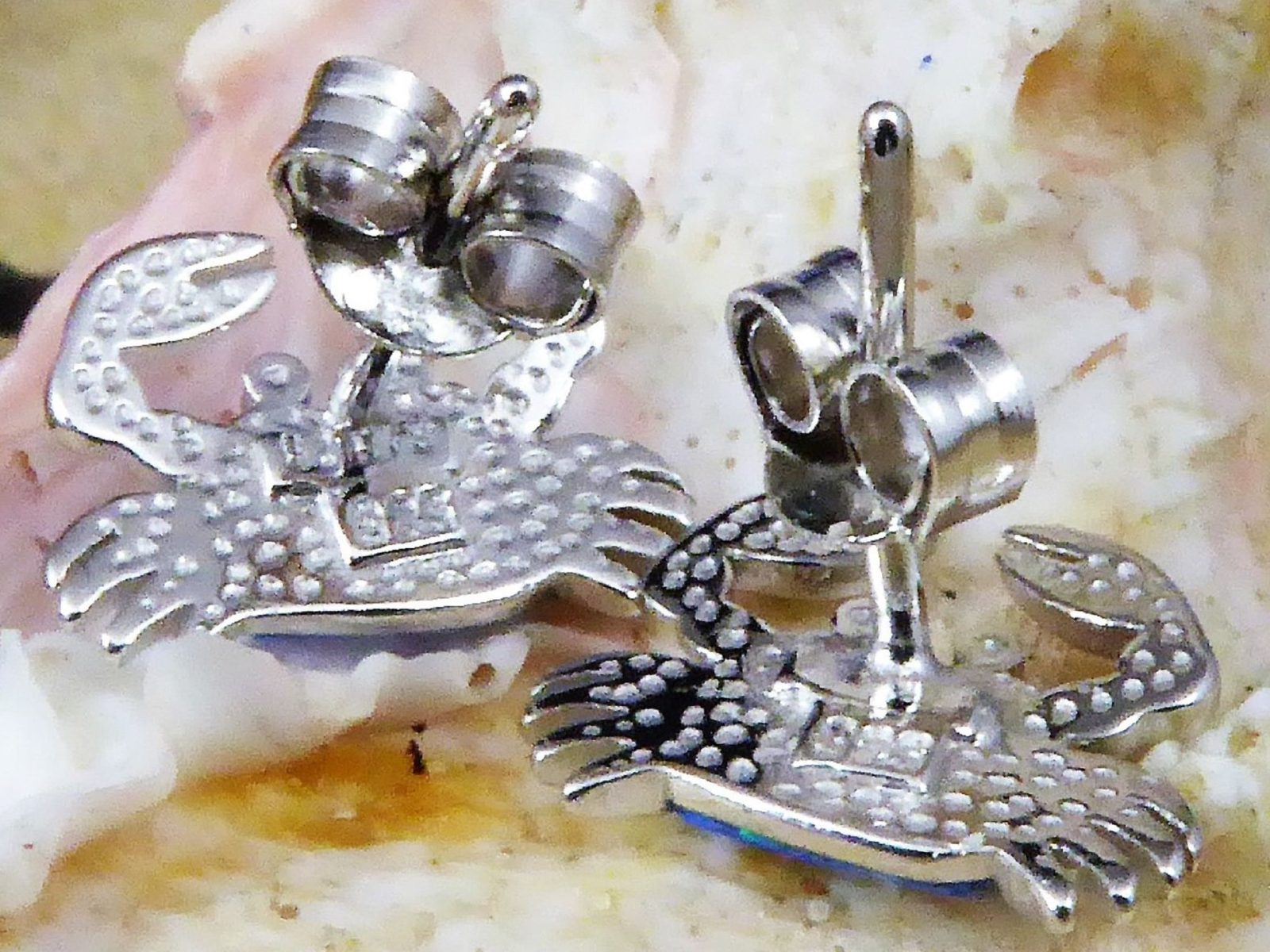 The Jewelry Network Caribbean Opal Crab Post Earrings feature detailed claws and textured shells, displayed on a seashell background with visible earring backs.