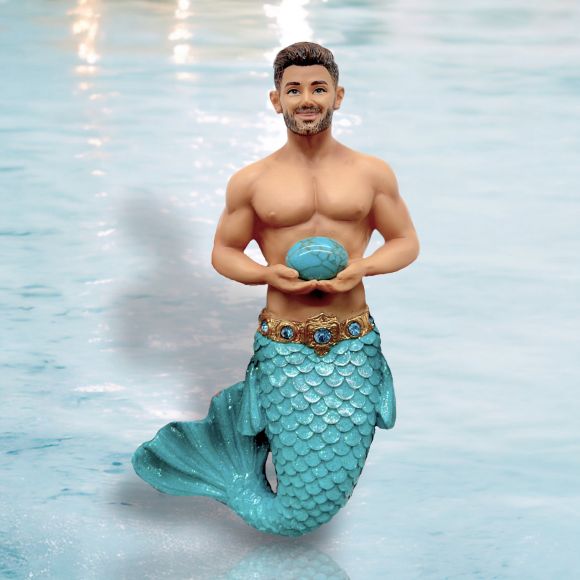 The December Diamonds December Birthstone-Turquoise Merman features a turquoise tail, ornate belt, blue seashell, and water-like backdrop. This hand-painted figurine has short dark hair and a trimmed beard—an exquisite collectible ornament.